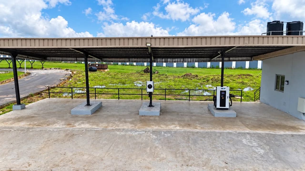 Charging bays under the steel canopy, with AC and DC chargers on concrete plinths